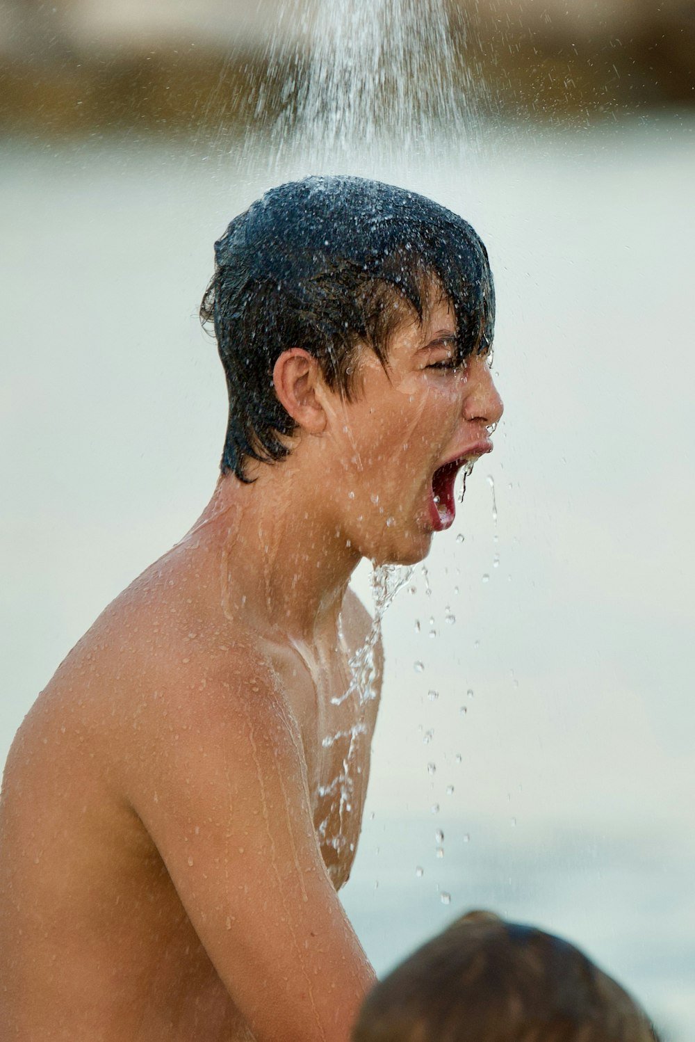 Homme avec des gouttelettes d'eau sur le visage après une douche froide, l'air alerte