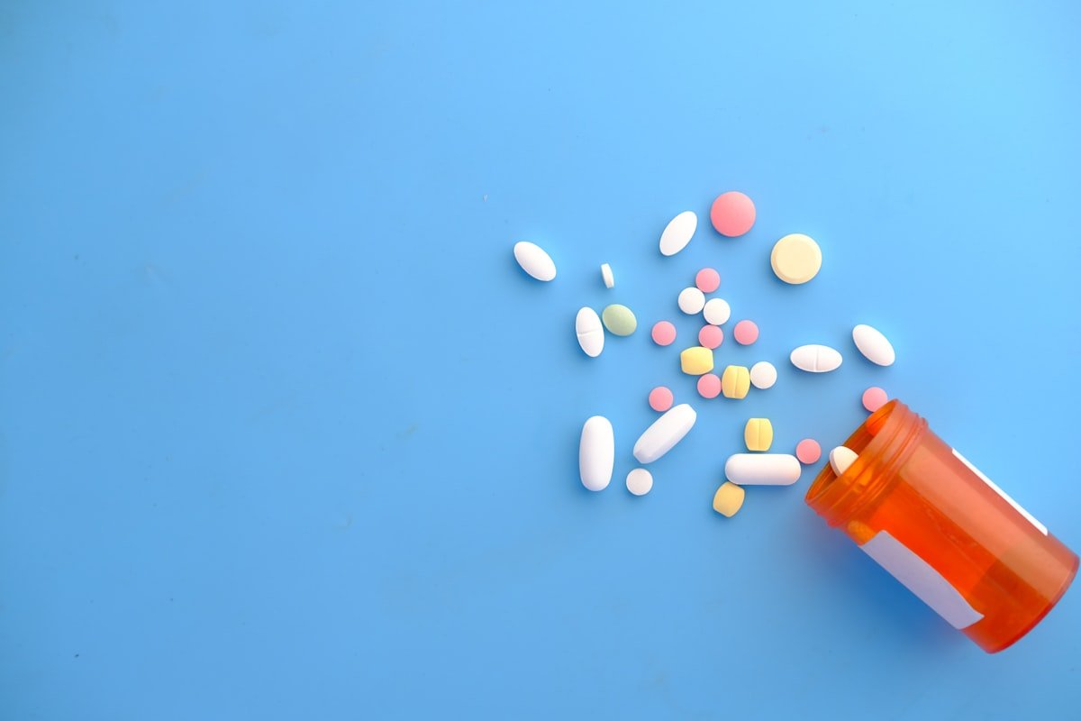 Gélules et compléments alimentaires colorés débordant d'un flacon