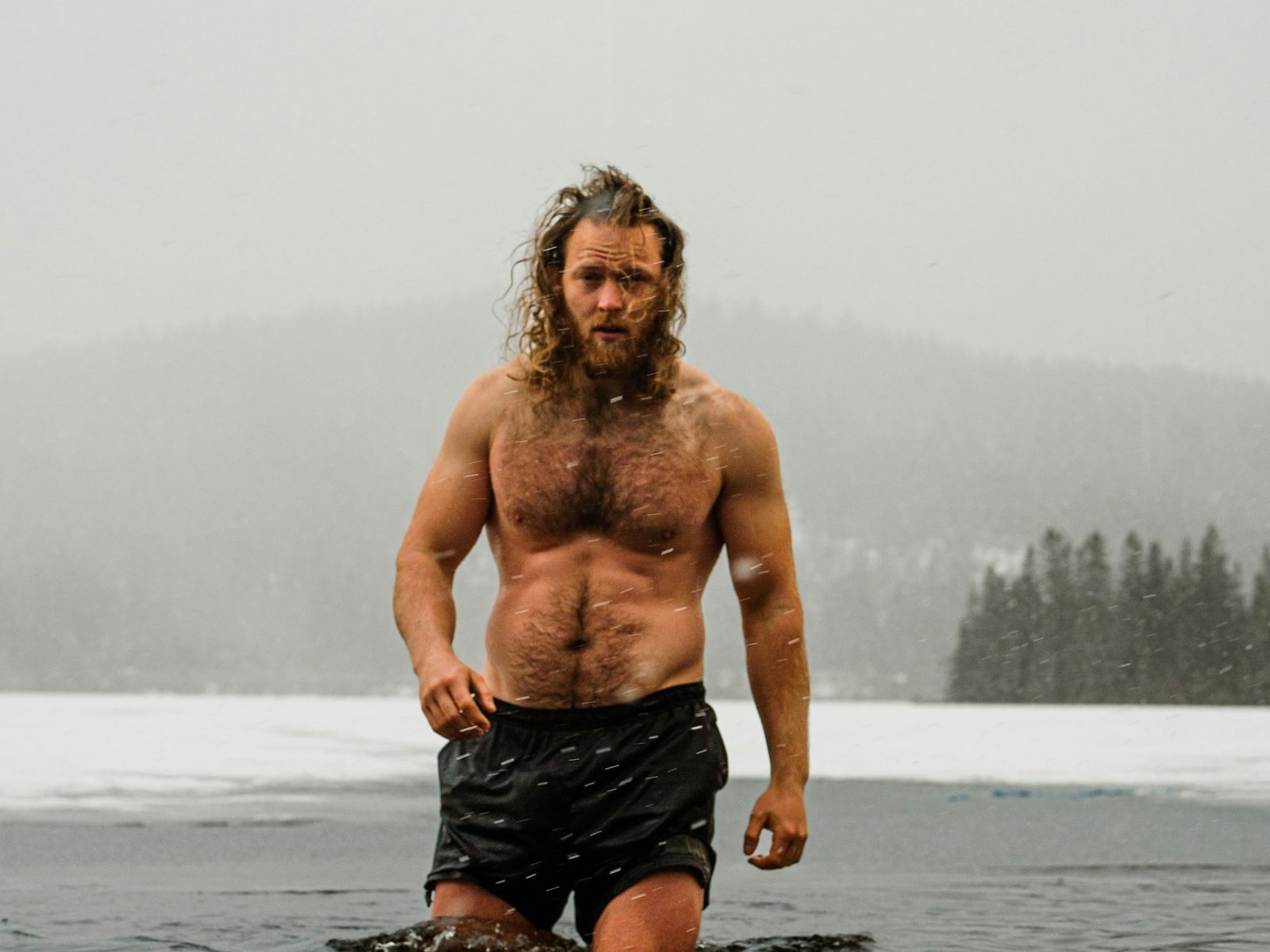 Homme entrant dans un lac glacé en hiver, le haut du corps hors de l'eau