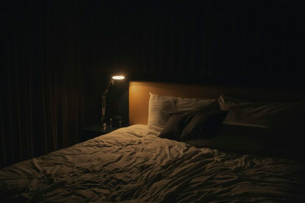 Lampe de chevet allumée à côté d'un lit, ambiance de soirée avant le coucher