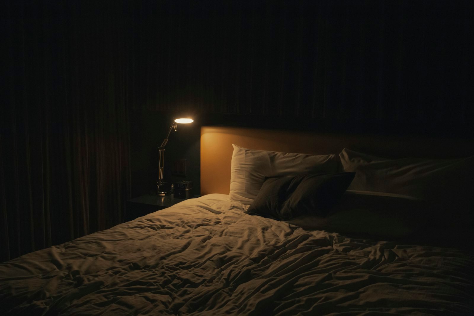 Lampe de chevet allumée à côté d'un lit, ambiance de soirée avant le coucher