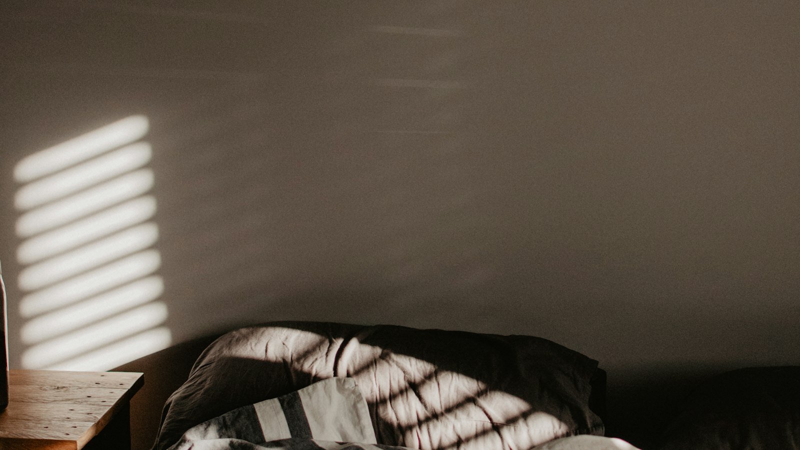 Lit défait aux draps rayés dans une chambre éclairée par la lumière du jour