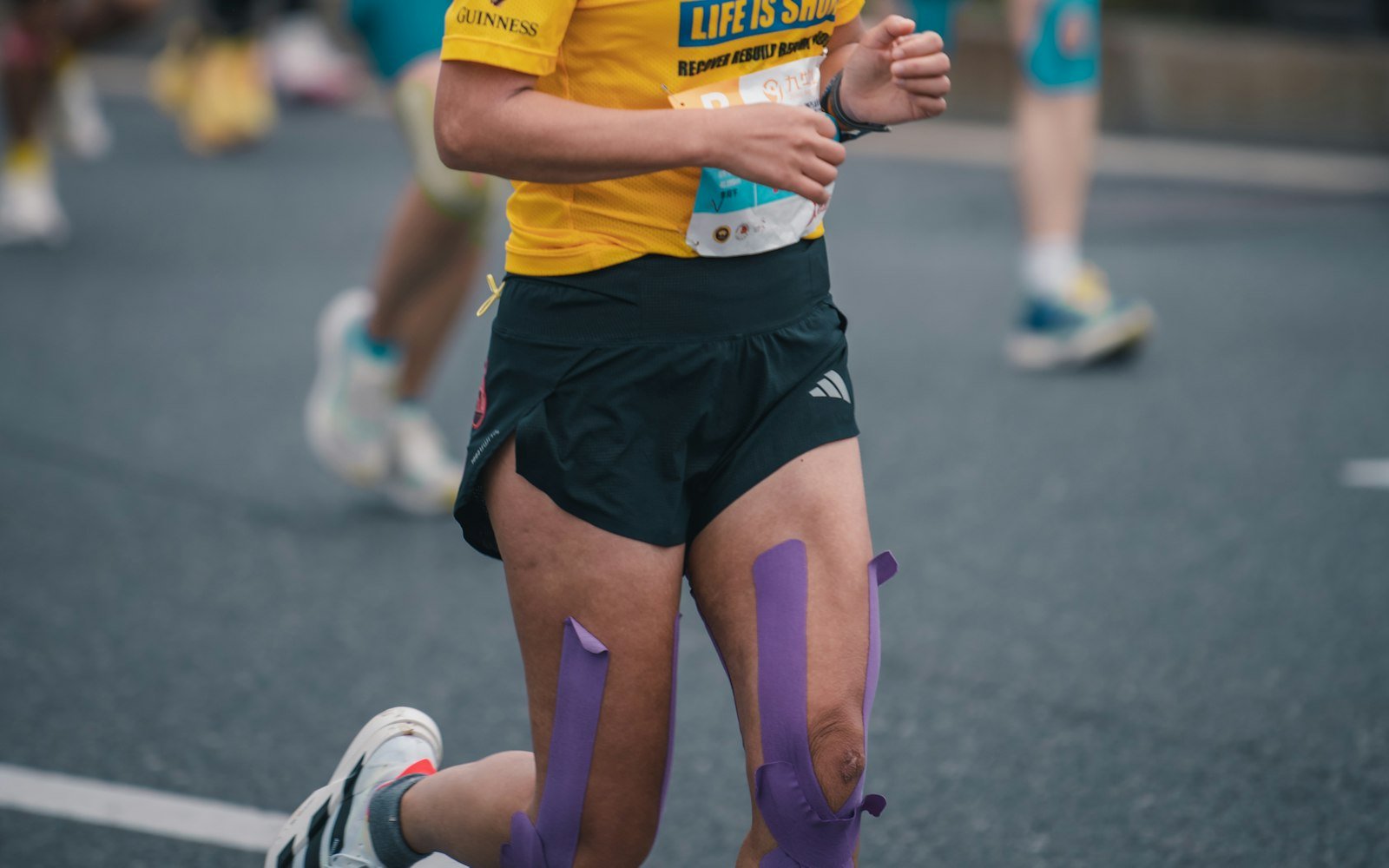 Coureuse de marathon en pleine course, bandes de strapping sur les jambes