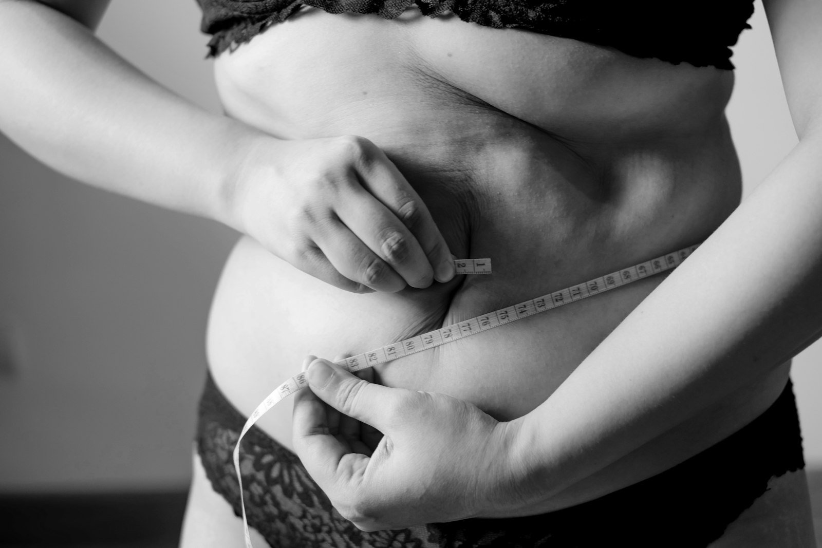 Personne mesurant son tour de taille avec un mètre ruban, illustration de la graisse localisée visée par la cryolipolyse