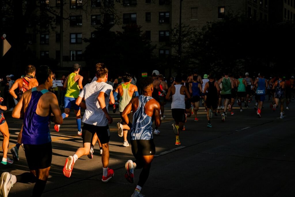 Coureurs de dos dans une rue de ville, en début de marathon, dans une lumière rasante