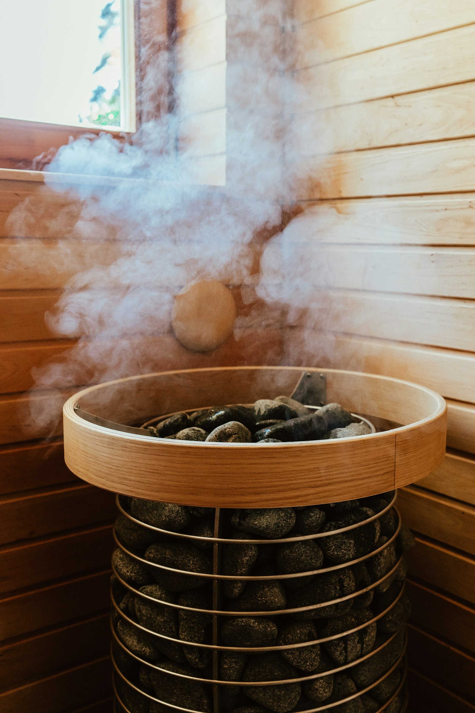 Vapeur s'élevant de pierres chaudes sur un poêle de sauna en bois