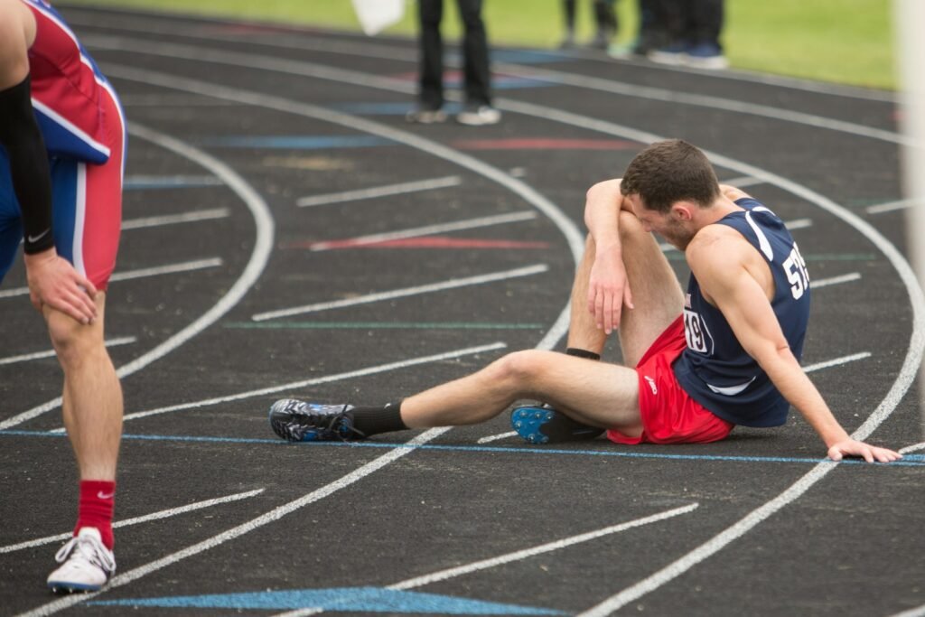 Coureur assis sur la piste d'athlétisme, épuisé après une course