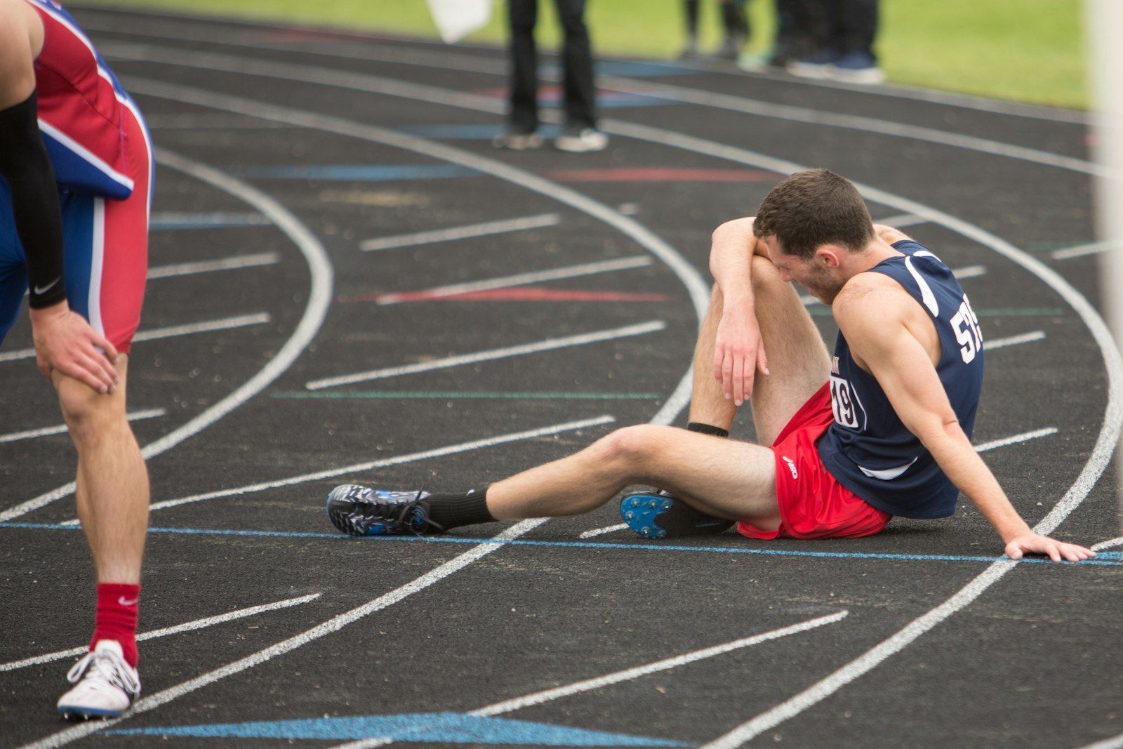 Coureur assis sur la piste d'athlétisme, épuisé après une course